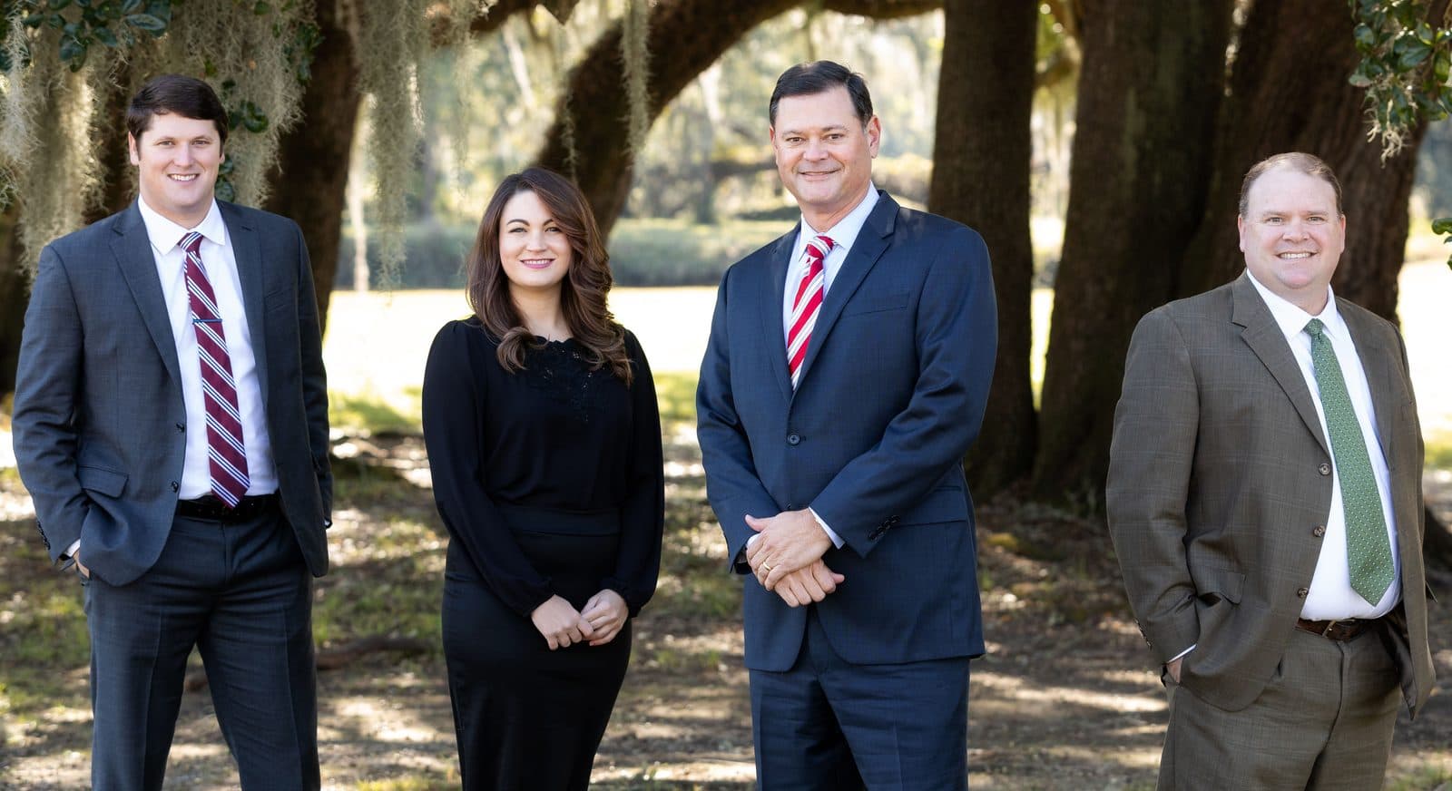 The four attorneys of The Tadda Law Firm standing outdoors under live oaks