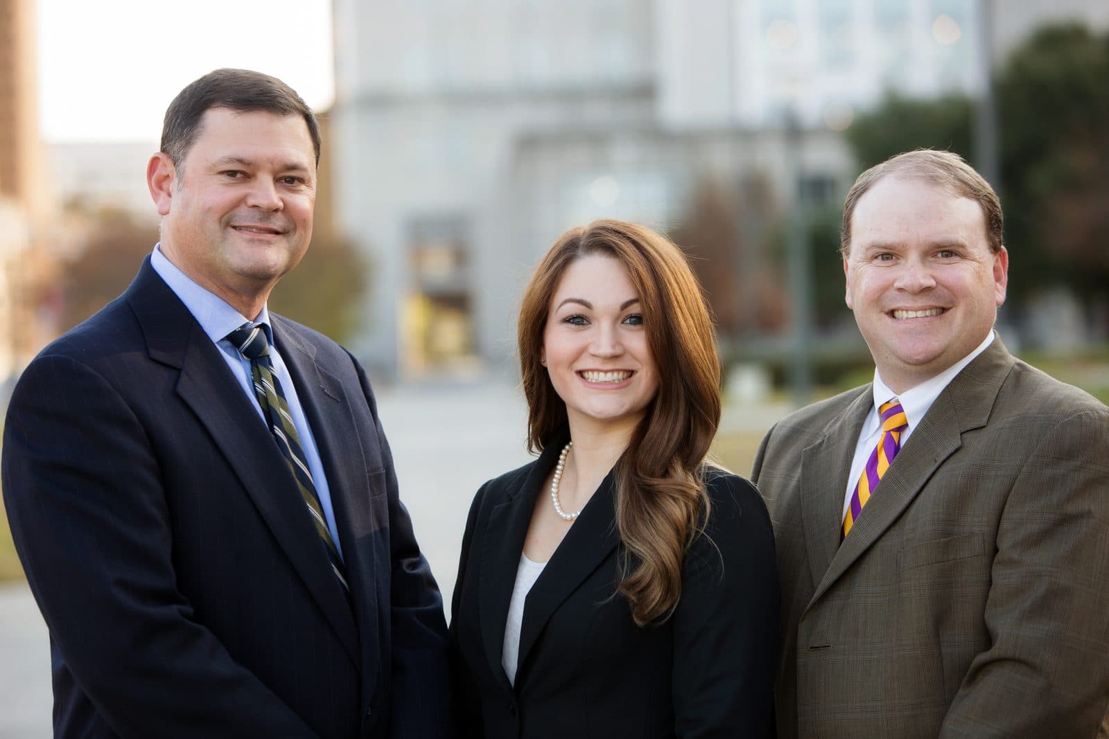 Erik Tadda, Sarah Tormey, and Jeremy Hader of The Tadda Law Firm standing together outdoors in front of a city building