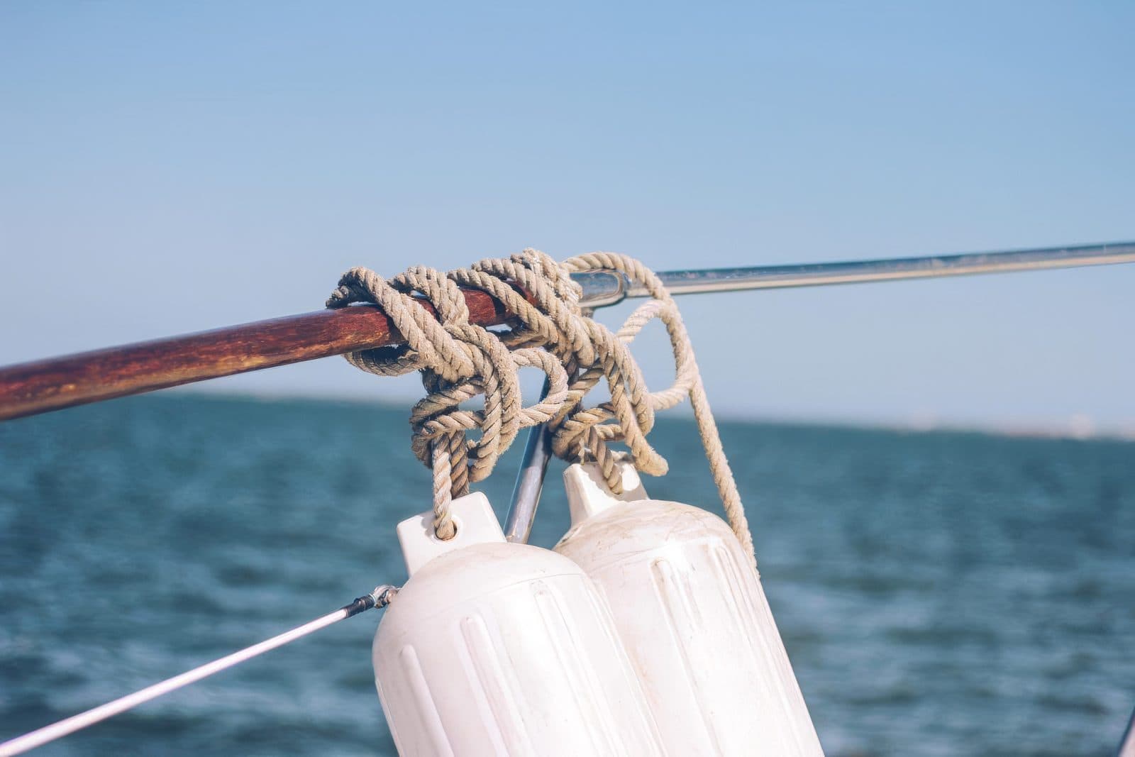 Mooring lines and fenders tied to the rail of a vessel on open water