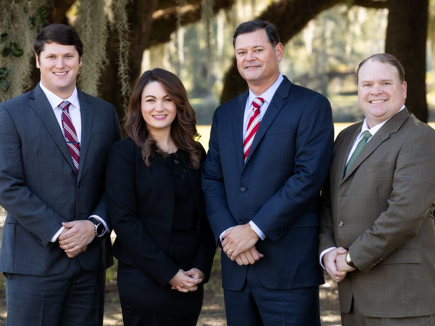 The four attorneys of The Tadda Law Firm standing together under live oaks