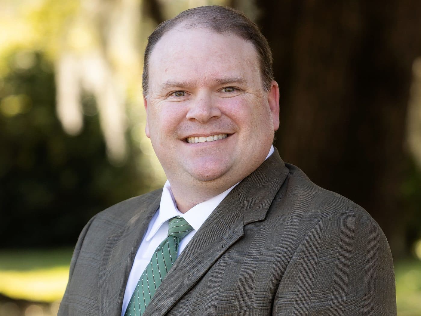 Attorney Jeremy Hader of The Tadda Law Firm outdoors under live oaks