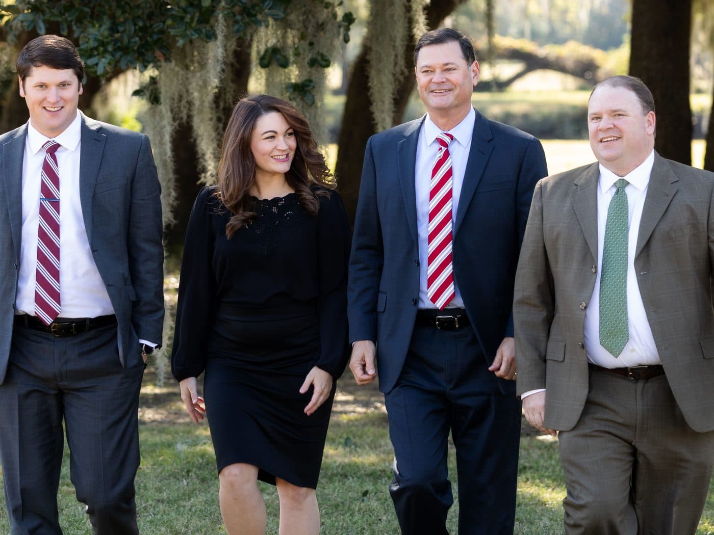 The four attorneys of The Tadda Law Firm walking together under live oaks