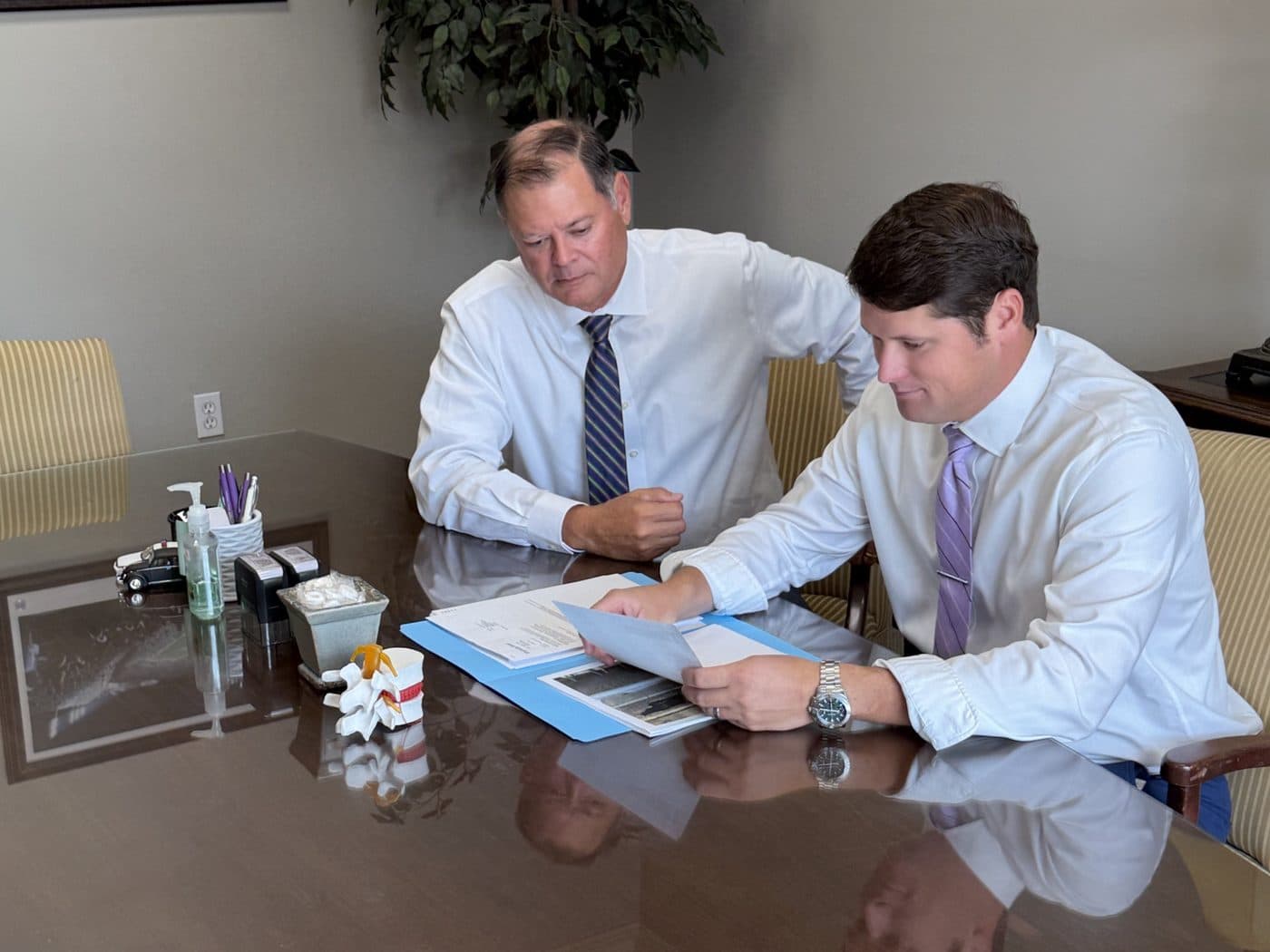 Erik Tadda and Rick Tadda going over paperwork at the office conference table