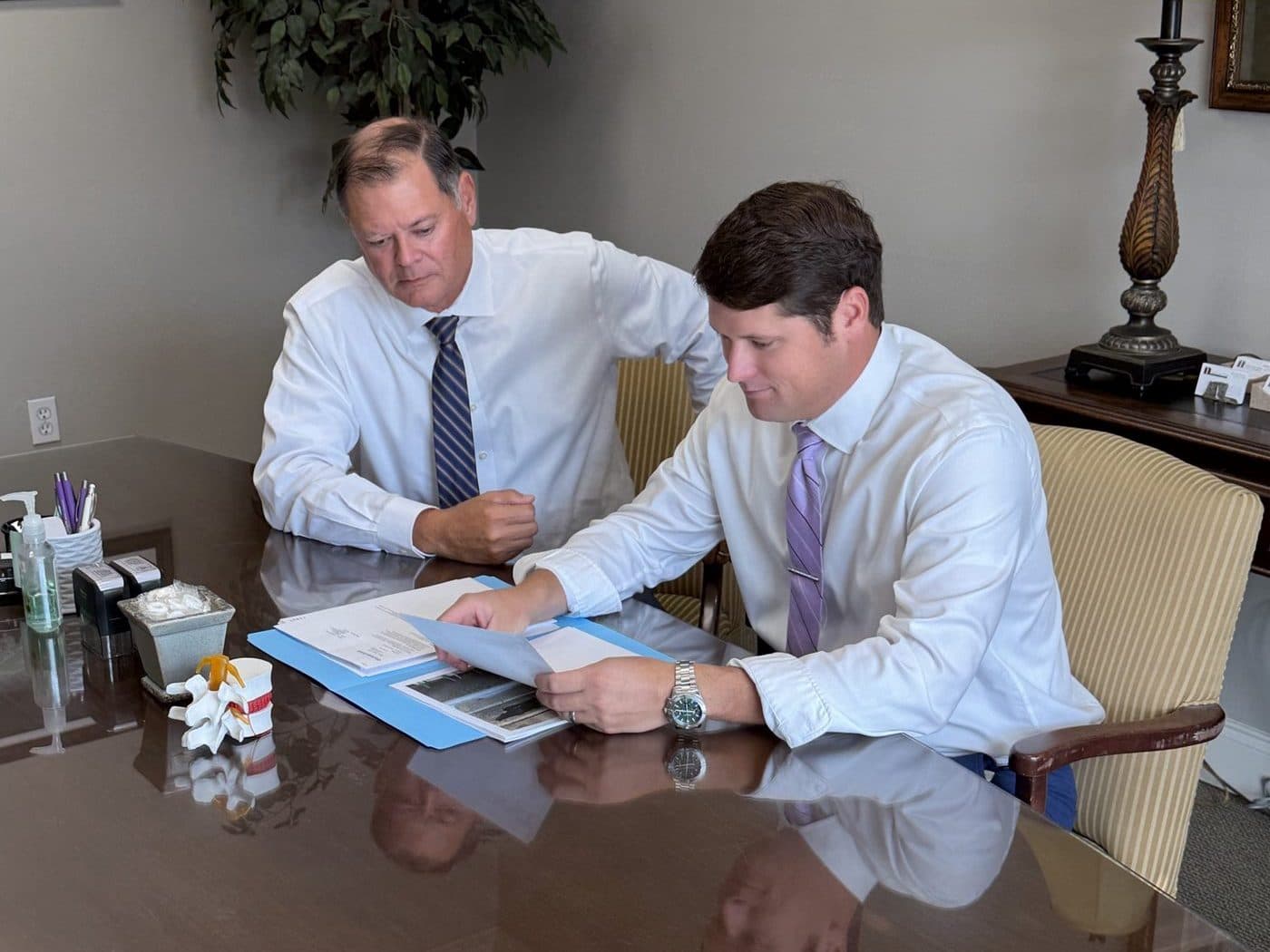 Erik Tadda and Rick Tadda reviewing a client file at a conference table