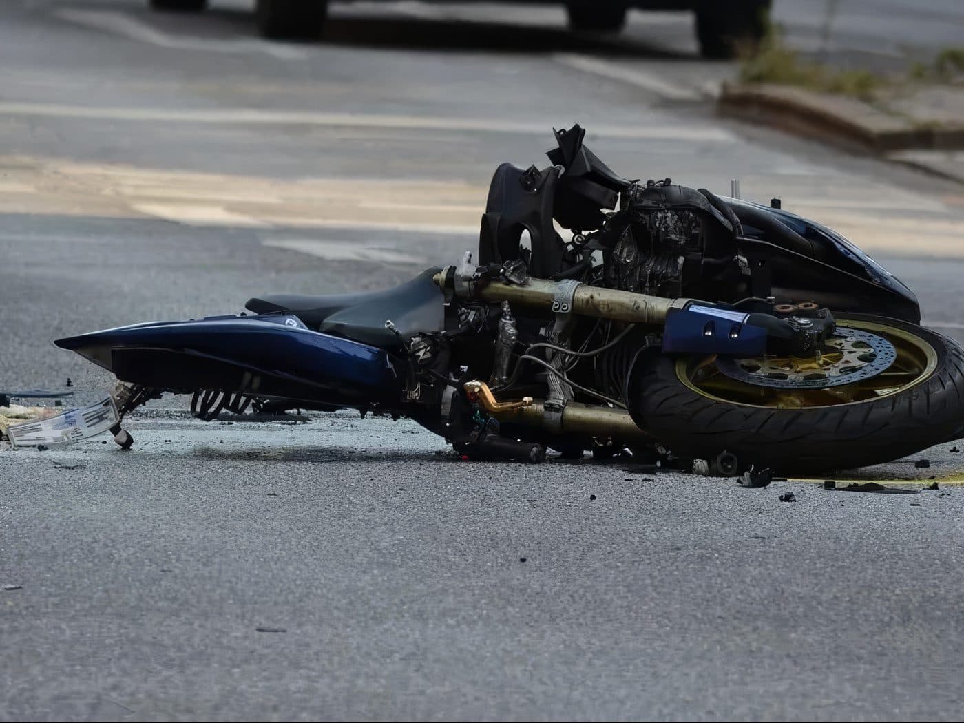 A motorcycle lying on its side in the street after a crash