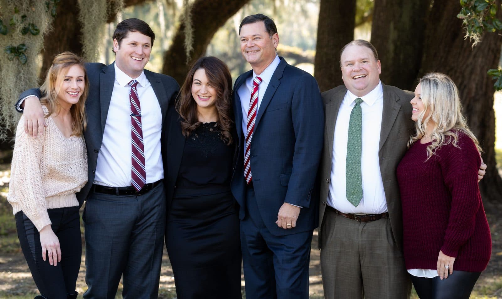 The attorneys and staff of The Tadda Law Firm together outdoors under live oaks